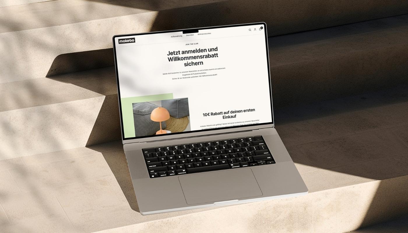 aufgeklappter Laptop auf einer Steintreppe. Auf dem Bildschirm ist die Anmeldung zum Newsletter Website von mokebo