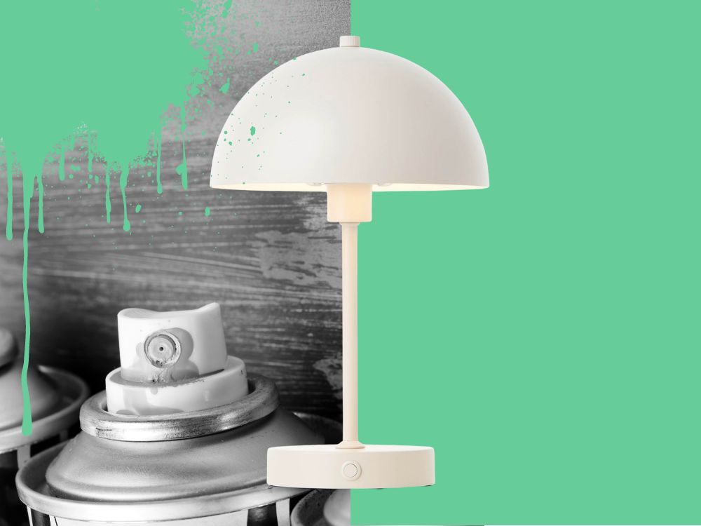 weiße Kabellose Tischlampe im Vordergrund, rechts grüne Farbe und links gestapelte Töpfe mit gesprenkelter grüner Farbe