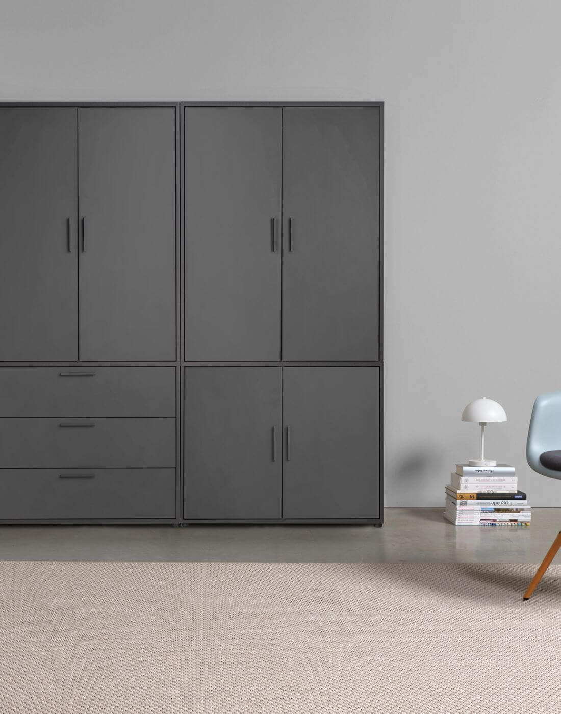 schwarzer Kleiderschrank an einer Wand, vier Türen oben, drei Fächer und zwei Türen unten