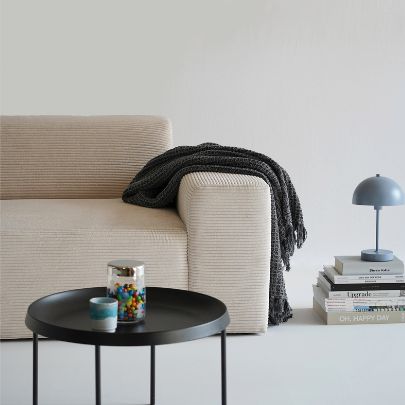 Cordsofa beige Armlehne über die eine schwarze Decke hängt