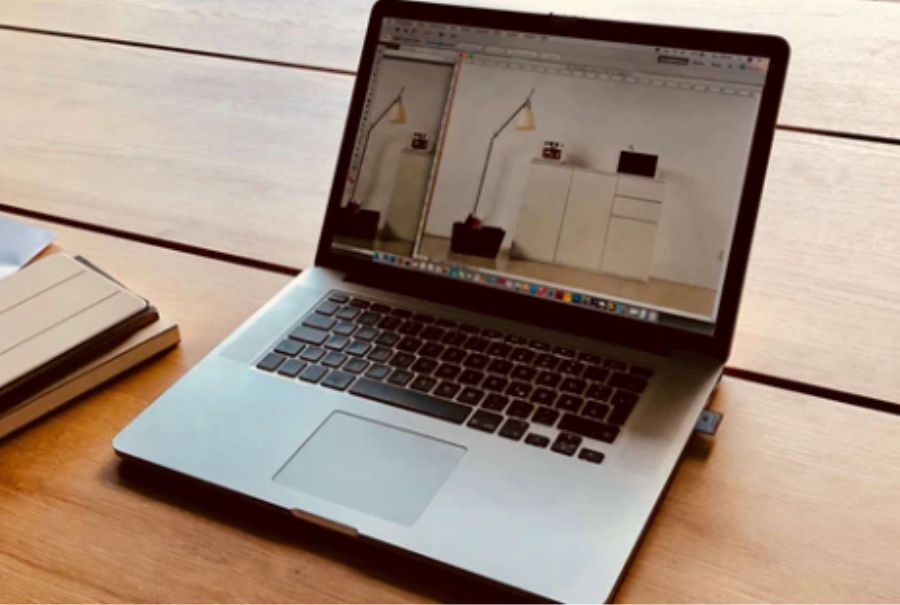 Laptop aufgeklappt auf einem Holztisch Bild mit Lampe und Kommode ist auf dem Bildschirm zu sehen