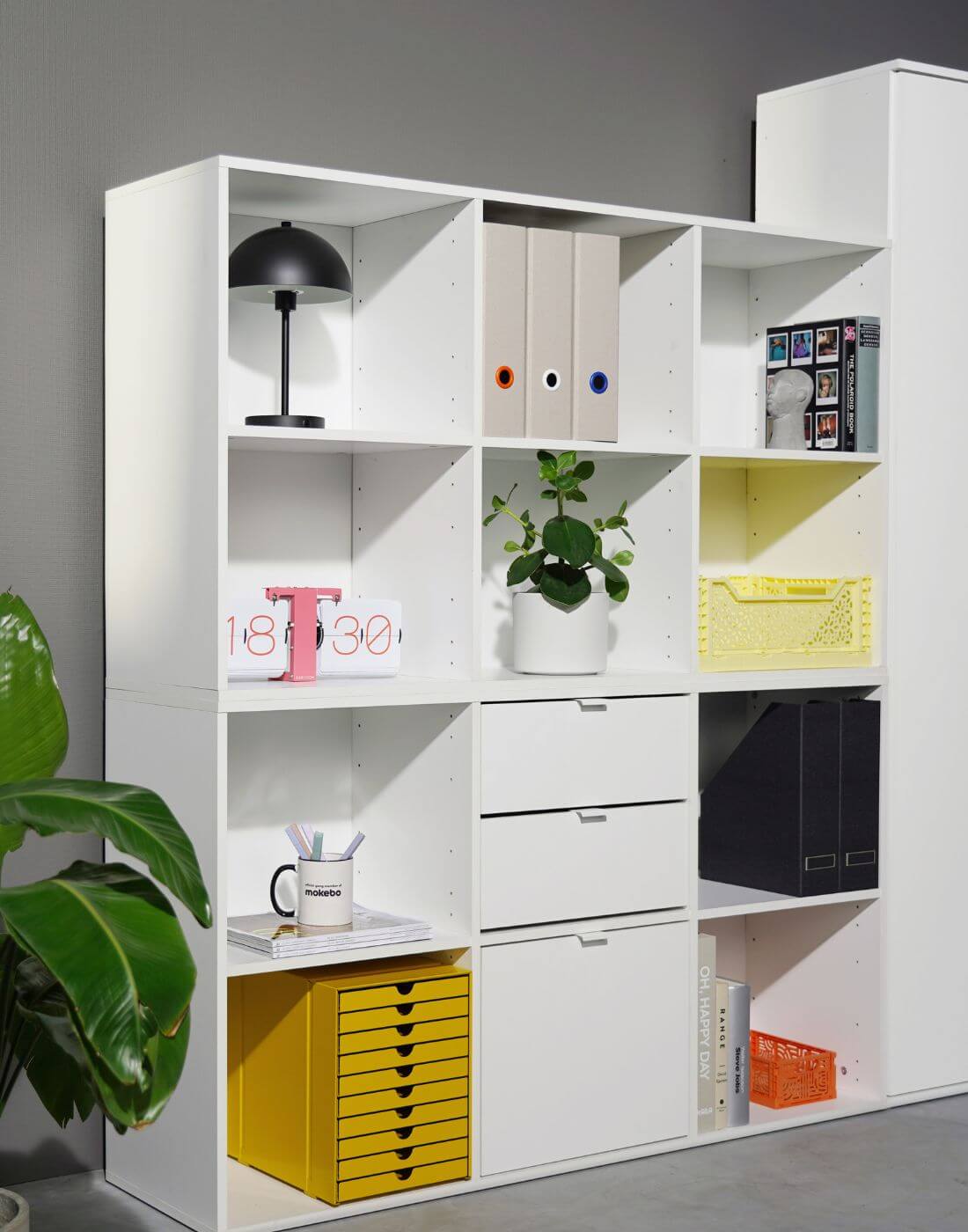 zwei weiße Aktenregale gefüllt übereinander an einer grauen Wand