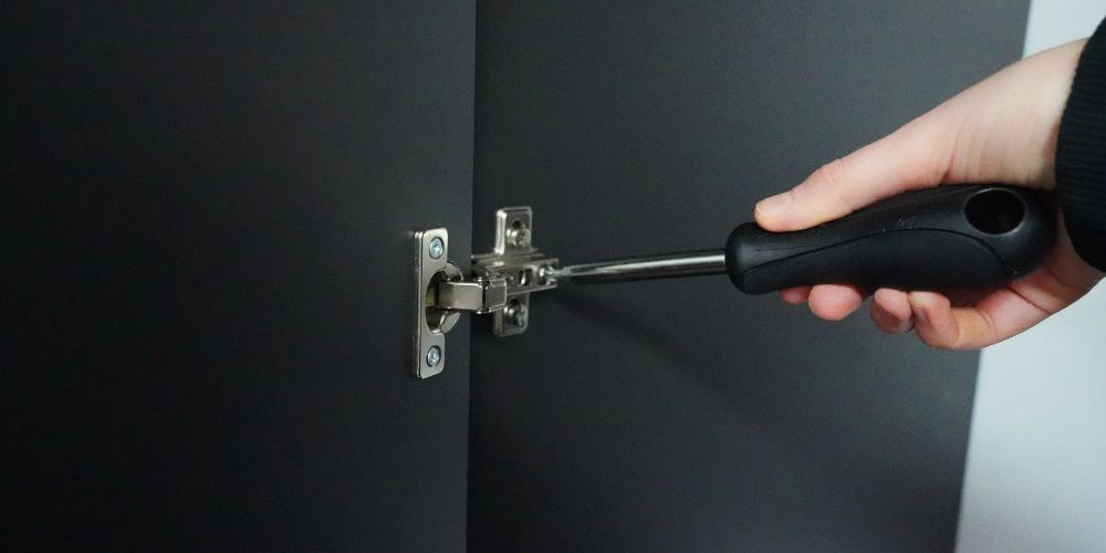 Scharnier an Schranktür Schraubenzieher steckt im Scharnier