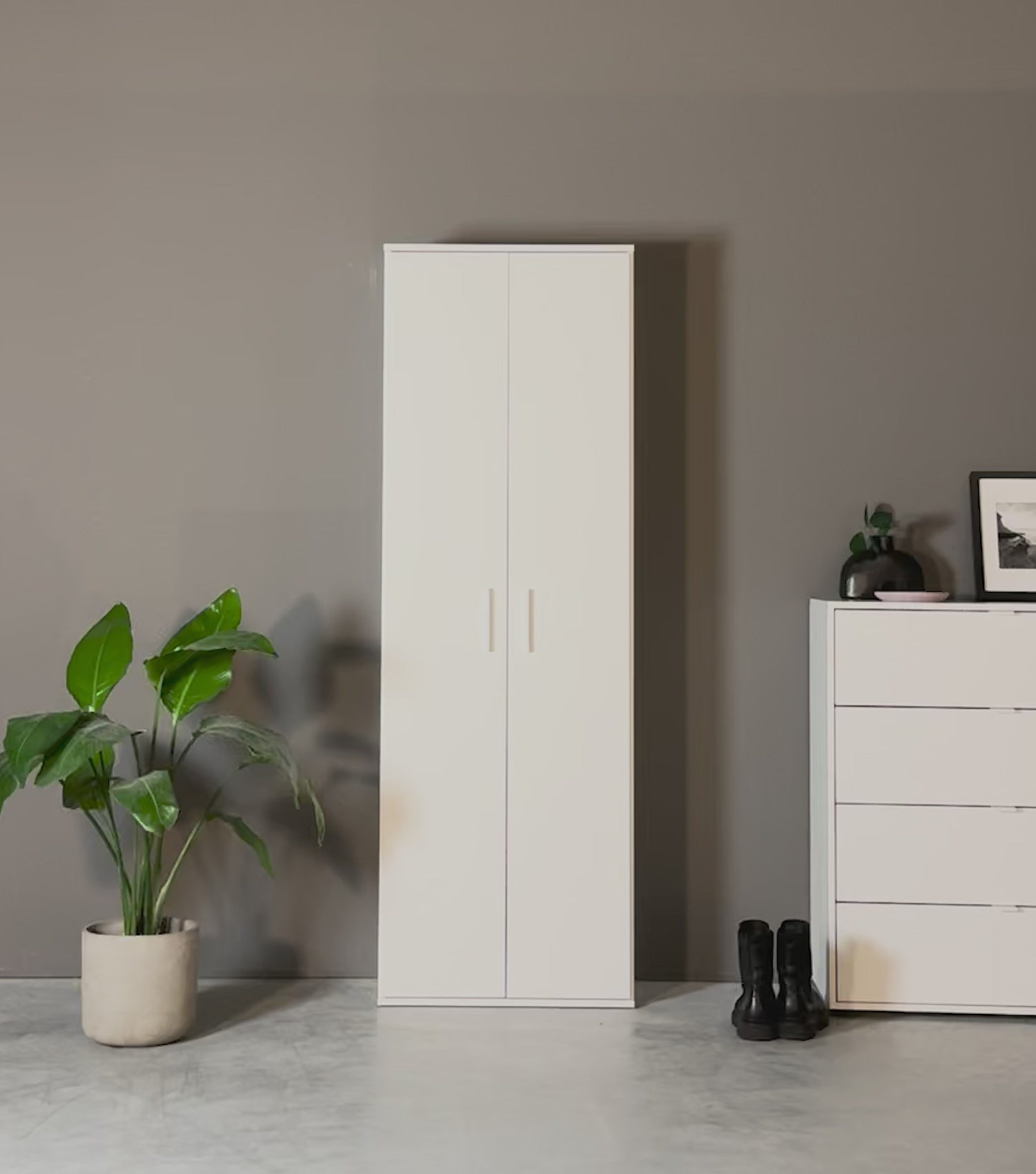 Produktvideo Mehrzweckschrank Garderobenschrank weiß mit Jacken, Taschen und Schuhen drin. Ein Paar Schuhe und eine Tasche werden hineingelegt. Eine Jacke wird in den Schrank aufgehängt. 